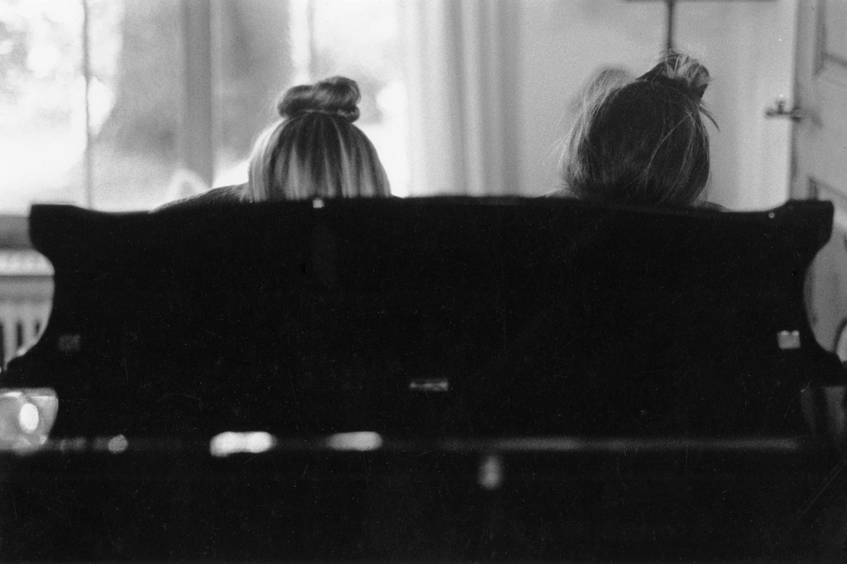 Eva 15 years old playing piano with her sister and showing just the top of their heads behind the piano